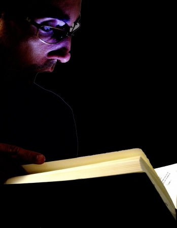Handsome young man with glasses caught reading a bookの写真素材