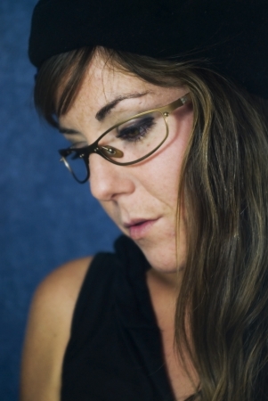 Portrait of a young woman reading a book with black shirt,  beret and blue backgroundの写真素材