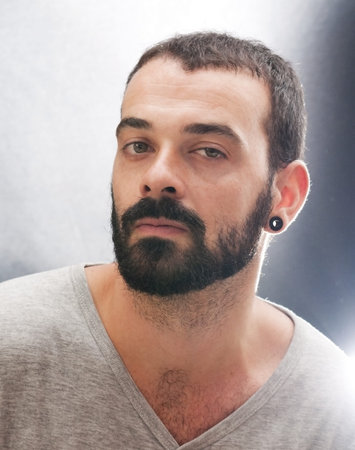 Backlit portrait of handsome guy with beard and grey shirt