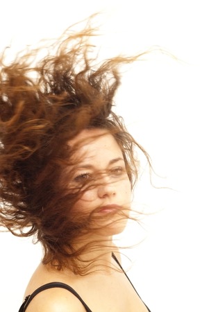 Portrait of a young  woman with black shirt  with her hair in the wind over white backgroundの写真素材