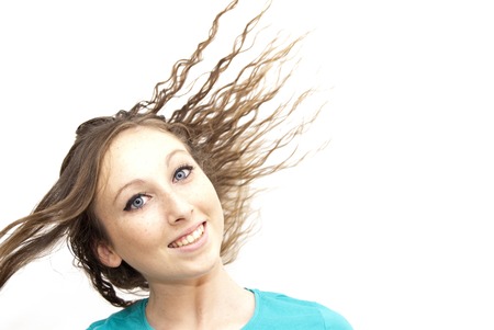 Pretty woman with blue eyes and green shirt and her hair moving with the wind on white backgroundの写真素材