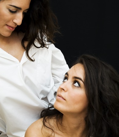 Portrait of  Two Friends Brunettes Women, looking in the eyes, With  White Shirts of Man  over black の写真素材