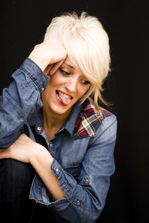 Beautiful woman with denim shirt and short white hair on black background. Pretty girl resting her face on her hand.の写真素材