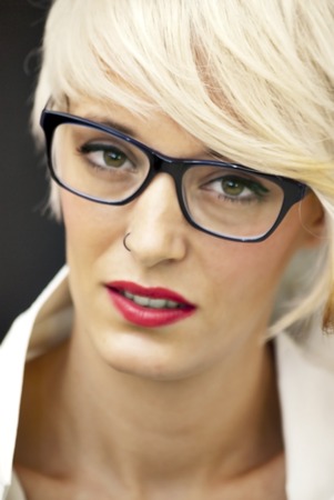 Beautiful woman with white man's shirt, glasses and short white hair on black backgroundの写真素材