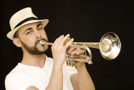 handsome guy playing a trumpet with beard and hat and  on black backgroundの写真素材