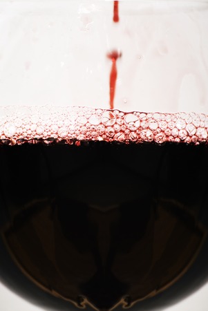 Glass of red wine with splash on white backgroundの写真素材