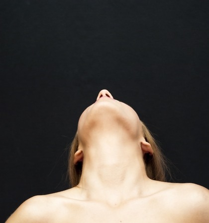 Portrait of Beautiful Young Woman Looking Up Over Black Backgroundの写真素材