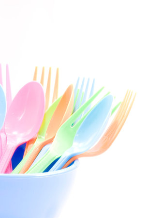 Plastic tableware consisting of spoon, fork and bowls over white backgroundの写真素材