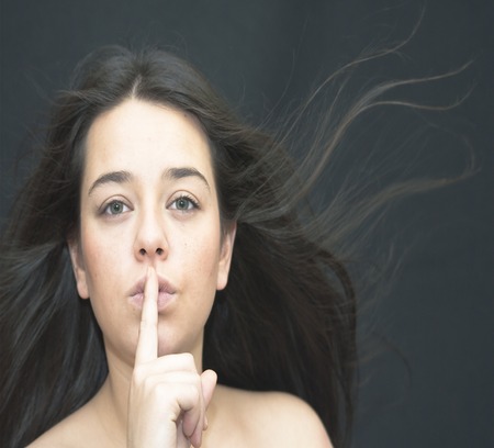 Portrait of Nice Young Woman  Making Silence Gesture Over White Backgroundの写真素材