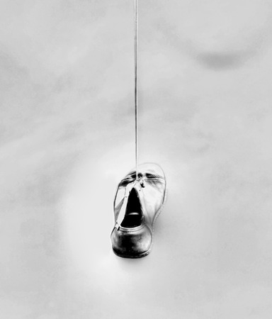 black and white old shoe hanging from their laces on a lamppost の写真素材