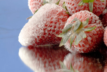 Frozen strawberries with ice on mirror surfaceの写真素材
