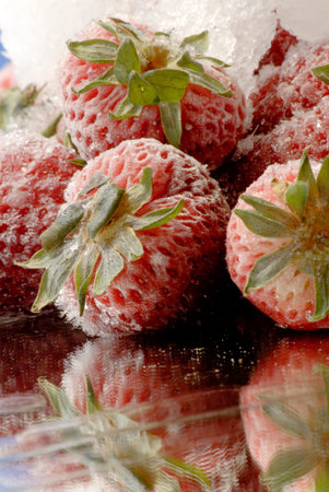Frozen strawberries with ice on mirror surfaceの写真素材