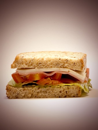 Sandwich  of cheese, ham, tomato and lettuce on white backgroundの写真素材
