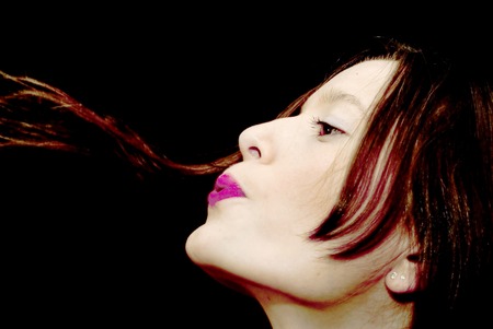 Portrait of Beautiful Young Woman Blowing Her Hair Over Black Backgroundの写真素材