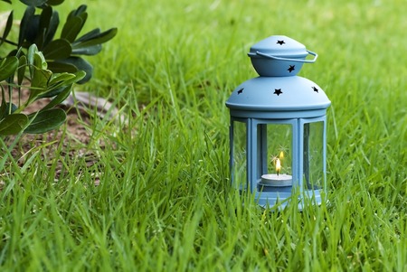 Blue Lantern, with burning candle inside, on green grass - stock imageの写真素材