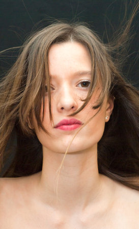 Portrait of Beautiful Young Woman Shaking Her Hair Over Black Backgroundの写真素材