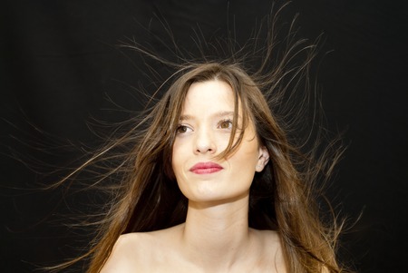 Portrait of Beautiful Young Woman Shaking Her Hair Over Black Backgroundの写真素材