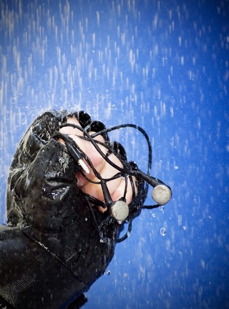 Gloved fist holding headphones to that raindrops fall like rain on blue background の写真素材