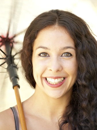 Beautiful woman with umbrella in a park on a sunny dayの写真素材