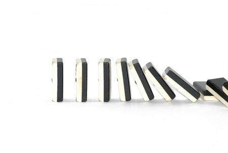 Row of dominoes falling over white backgroundの写真素材