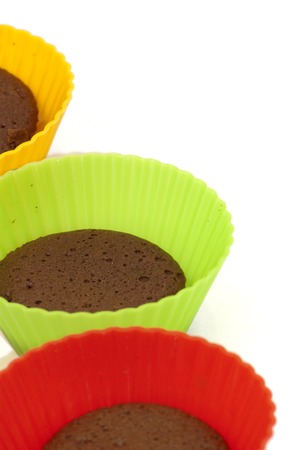 Chocolate muffins in silicone holders of many colors on white backgroundの写真素材