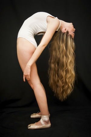 Ballet dancer performing dance exercises on black backgroundの写真素材