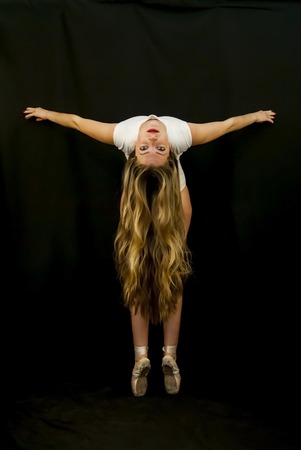 Ballet dancer performing dance exercises on black backgroundの写真素材