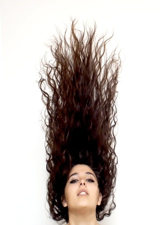 Portrait of Beautiful Young Woman Shaking Her Hair Over White Backgroundの写真素材