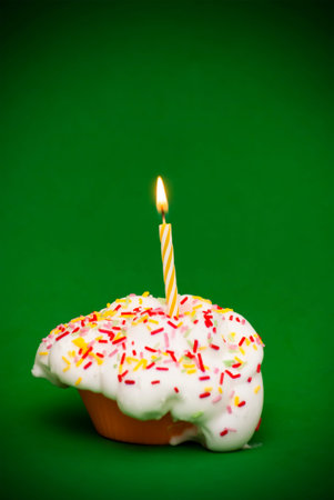 Cupcake with a lit candle over green backgroundの写真素材