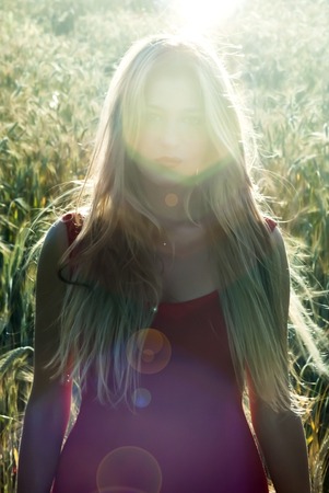 Beautiful blond woman in a wheat field at sunset  backlitの写真素材