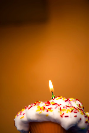 Cupcake with a lit candle  in an moody atmosphereの写真素材