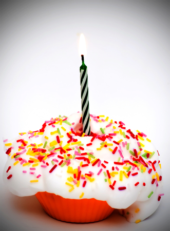 Cupcake with a lit candle over white backgroundの写真素材