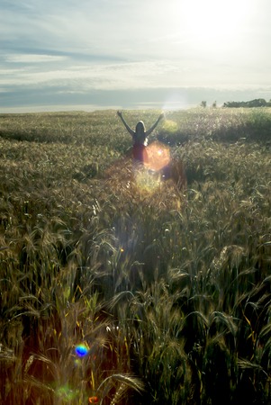 Beautiful blond woman in a wheat field at sunset  backlitの写真素材