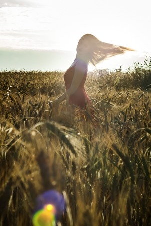Beautiful blond woman in a wheat field at sunset  backlitの写真素材
