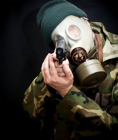 Soldier with a gun, gas mask and camouflage suit on dark backgroundの写真素材