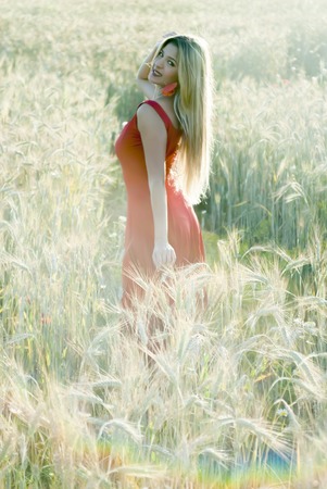 Beautiful blond woman in a wheat field at sunset  backlitの写真素材