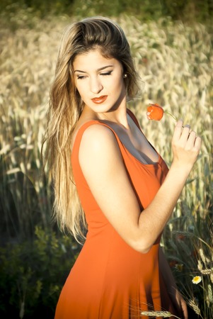 Beautiful blond woman in a wheat field at sunset  backlitの写真素材