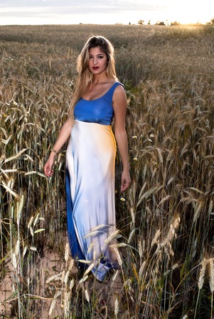 Beautiful blond woman in a wheat field at sunset  backlitの写真素材