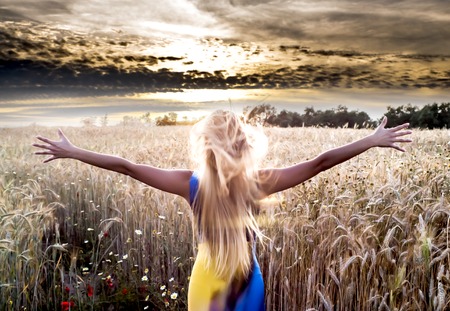 Beautiful blond woman in a wheat field at sunset  backlitの写真素材