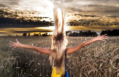 Beautiful blond woman in a wheat field at sunset  backlitの写真素材