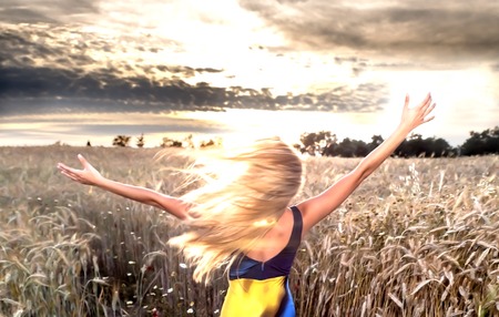 Beautiful blond woman in a wheat field at sunset  backlitの写真素材