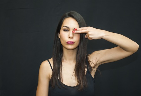 Portrait of Beautiful Young Woman covering one eye with her hand Over Black Backgroundの写真素材