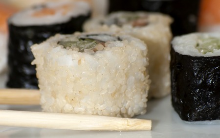 Different japanase sushi rolls on white plate with chopsticの写真素材