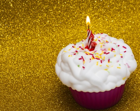 Cupcake with a lit candle over bright backgroundの写真素材