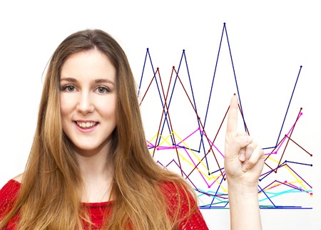 Portrait of beautiful young woman pointing her finger towards a financial graphs on white backgroundの写真素材