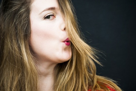 Portrait of Beautiful Young Woman  blowing her hair Over Black Backgroundの写真素材