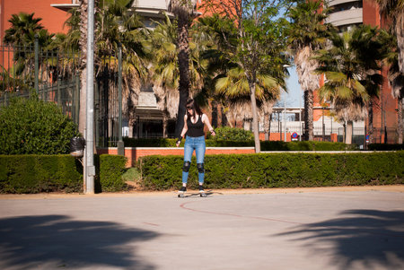 Beautiful young woman practicing with the skateboard on the street on a sunny day