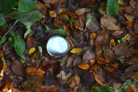 Fallen colorful autumn leaves and a rusty can on the groundの写真素材