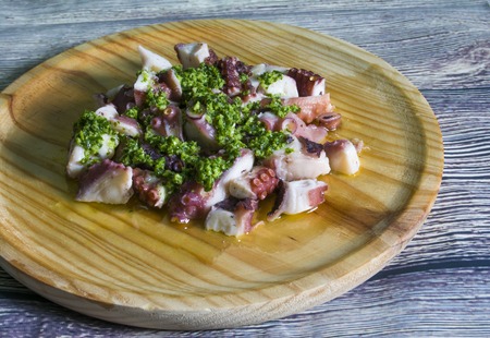 Octopus with paprika, typical dish of Spain, on a wooden plate on a wooden tableの写真素材