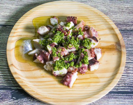 Octopus with paprika, typical dish of Spain, on a wooden plate on a wooden tableの写真素材